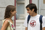 Dos programadores, un chico moreno con camiseta blanca y una chica de pelo castaño con camiseta de tirantes amarilla, hablan a la salida del trabajo.