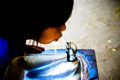 Un niño o niña bebiendo agua que sale de una fuente.
