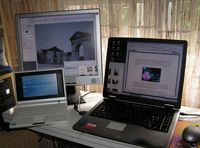 Foto que muestra en primer plano un portátil y un notebook abierto y una pantalla TFT sobre un escritorio.