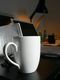 Mesa de trabajo con un ordenador al fondo y una taza en primer plano