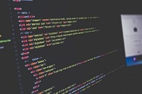 Ilustración en la que se ve una pantalla de ordenador mostrando un código HTML con la sintaxis coleradda y el fondo negro