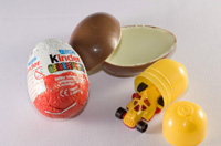 Ilustración de un Huevo kinder abierto mostrando la envoltura de papel de aluminio, el huevo de chocolate y leche partido por la mitad, el envoltorio de plástico de la sorpresa y la sorpresa que en la foto es un coche miniatura deportivo.