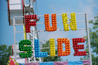 Ilustración en la que se ve un cartel de feria que pone “FUN SLIDE” en letras de colores. 