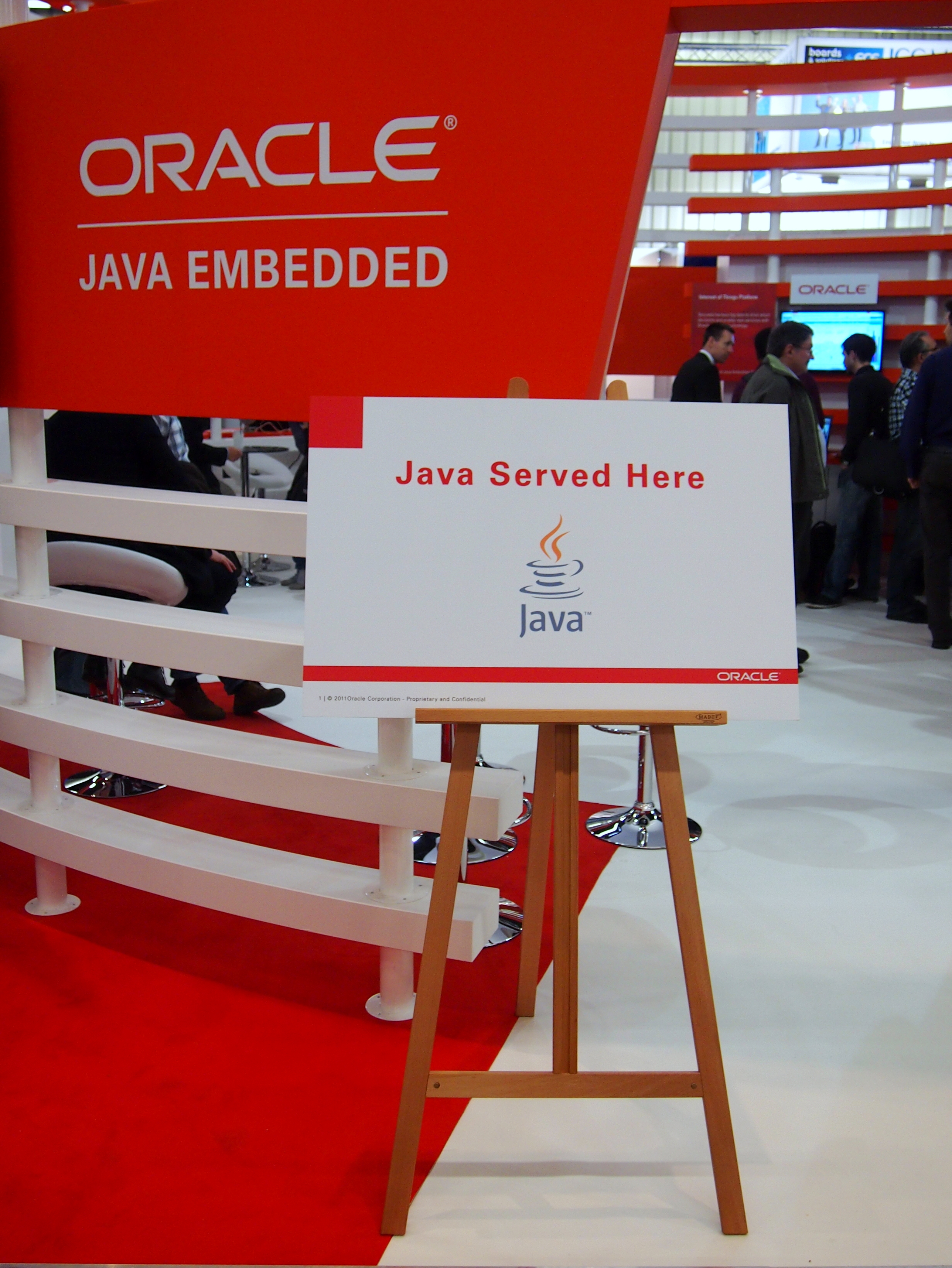 Oracel Java Imagen donde se muestra un cartel en rojo de oracle y en el centro una atril con un cartel conteniendo el dibujo en azul de una taza de café, el logo de java