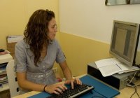 María sentada, escribiendo con un ordenador, mirando a la pantalla y tecleando.