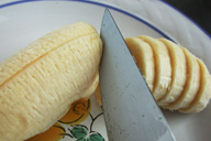 Fotografía que muestra un cuchillo cortando en rodajas un plátano.