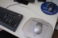 Ratón sobre esterilla ergonómica. Imagen, de un puesto de trabajo donde se destaca le ratón sobre una alfombrilla ergonómica.