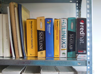 En la foto se ve una estantería con las cajas de algunos programas: Windows XP, dos versiones de Linux, el antivirus Norton y alguno que otro más.