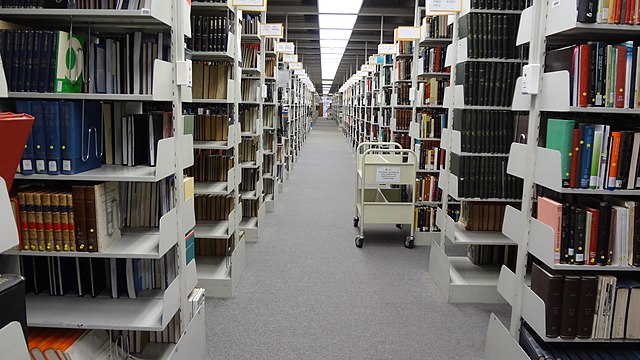 Imagen que muestra un pasillo de estantería con libros.