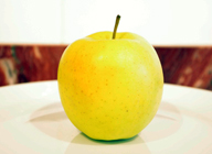 Imagen de una manzana sobre un plato blanco.