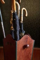 Paragüero de madera marrón  con  varios paraguas.