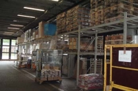Local con estanterías, llenas de mercancías, que es utilizado por la empresa como almacén .