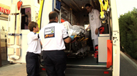 Imagen de un ambulancia con las puertas abiertas y un herido entrando en una camilla.