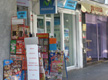  Imagen de una calle comercial, donde se observa la fachada de varios comercios minoristas, posiblemente sometidos al régimen de recargo de equivalencia. En primer plano se observa una pequeña tienda de venta de prensa y golosinas. 