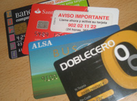 En esta imagen puedes ver cuatro tarjetas, dos son bancarias, y las otras dos son comerciales. Son de distintos colores y diseños, y aparecen repartidas sobre una superficie de color marrón.
