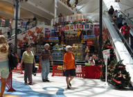 Centro comercial con gentes paseando y bajando las escaleras mecánicas.