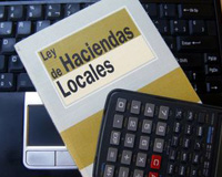Ordenador, libro de la ley de haciendas locales y calculadora.