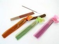  Se pueden ver dos quemadores de incienso en el fondo y tres juegos de varitas de incienso envueltos en bolsitas color naranja, verde y rosa respectivamente.    