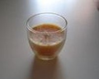  Se observa un vaso de cristal redondeado y color melocotón, con una mecha en su interior.    