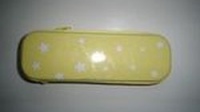  Estuche color amarillo con motivos en blanco.    