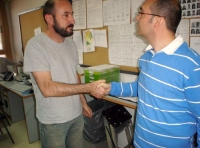 Relaciones internas. En la foto se ve a dos trabajadores de pié en una oficina charlando y dándose la mano.