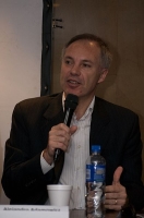 Comunicación. Se observa a un hombre de mediana edad, sentado, con un micrófono en la mano dando una conferencia.