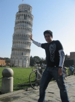 Pisa. Se muestra un joven en primer plano con la torre de Pisa de fondo, semejando como si el propio joven la estuviera sujetando.