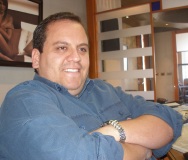 Cardenas. En la imagen se observa a un hombre de mediana edad, de complexión fuerte, sentado en una mesa de despacho, sonriente y con un jersey de color azul de lana.