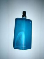 La imagen muestra uno de los perfumes que comercializa PROCOS SL. Es un frasco alargado, de color azul con el dispensador de color negro.