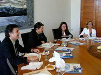 Grupo de personas debatiendo ante una mesa de reuniones.