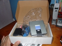 Caja con equipo de sistema VoIP de megafonía con  medio de un adaptador.