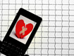 Un móvil com uma imagen em la pantalla de un corazón roto pegado com dos tiritas.