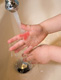 Fotografía de la mano de un niño con una mancha roja que representa una quemadura colocada bajo el chorro de agua fría de un lavabo.