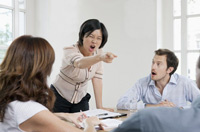 Mujer comportándose agresivamente en una reunión de trabajo.