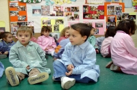 Fotografía de un grupo de niños y niñas sentados sobre el suelo de un aula realizando una actividad educativa.