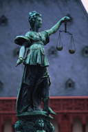 Foto que muestra la estatua de la justicia, ubicada en Alemania, representada por una mujer que sostiene con su brazo izquierdo una balanza, símbolo de la justicia.