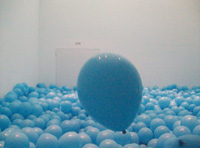 Fotografía de una sala llena de globos azules con un globo en el centro que se eleva por encima de los demás.