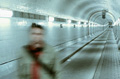 Fotografía de una estación de metro y, en primer plano, la imagen borrosa de un hombre.