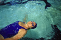 Fotografía de una señora mayor nadando en una piscina.