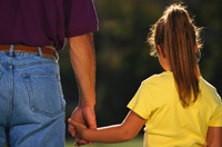 Fotografía de un padre y su hija caminando de espaldas cogidos de la mano.