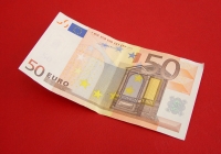 Billete de 50 euros depositado sobre un fondo rojo.