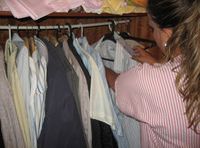 Esther (22 años, rubia, pelo largo recogido en una coleta y uniforme de TAPD a rayas rosas y blancas) está colocando una camisa en un armario, utiliza una percha. En el armario pueden verse más camisas y otras prendasde diferentes colores.