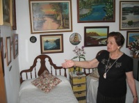 En la habitación de María. María de perfil, mujer de 72 años vestida de negro.