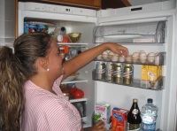 Esther (22 años, rubia con el pelo recogido y uniforme a rayas rosas y blancas) coloca los huevos en la nevera.