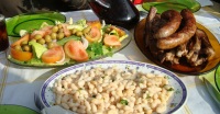 Primer plano de alimentos : Plato de costillas de cordero y butifarra con alubias y ensalada de guarnición.