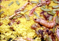 Primer plano de una paella con gambas, habichuelas, carne etc.