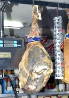 Primer plano de un jamón curado que cuelga en una charcutería.