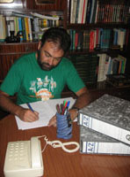 Leonardo, chico de unos 36 años, moreno y con barba y camiseta verde. Permanece sentado y trabajando en su escritorio.