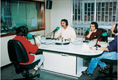 En el centro  la foto aparece un locutor de radio en un estudio de radio y frente a él otra personana a quién realizan una entrevista.