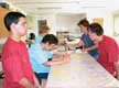 En la imagen aparecen alredor de una mesa varios jóvenes con discapacidad intelectual realizando un taller.